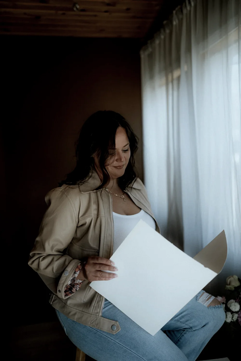 Cydnie Jocelyn seated in low light, reading a sheet of paper, face turned away from the camera.