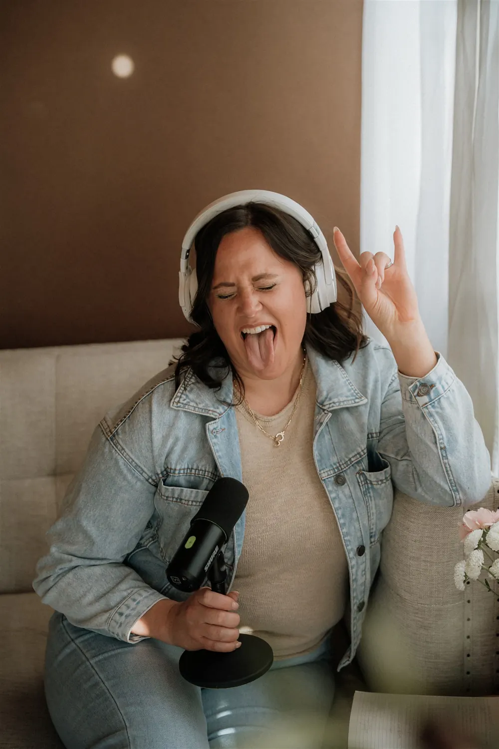 Cydnie singing into a microphone with headphones on, eyes closed