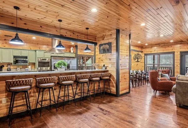 A long counter with a row of leather stools, open to the kitchen on one side and the living room on the other.