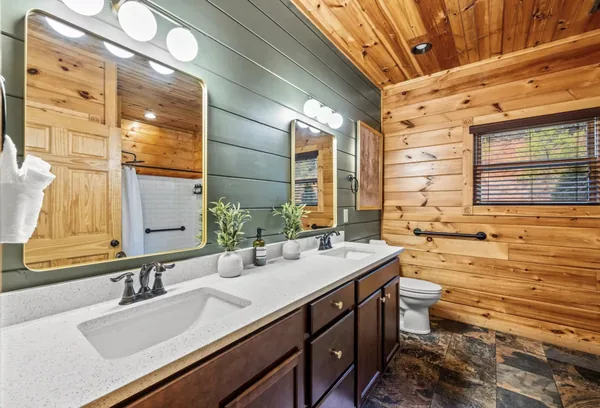 A double vanity under a wide mirror against a green panelled wall.