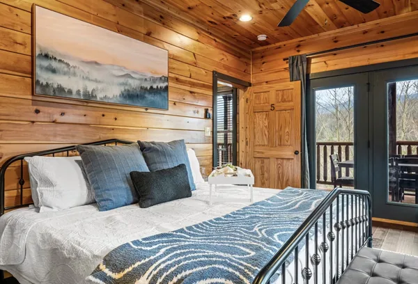 A bedroom with a framed ridgeline above the headboard and doors onto the balcony.
