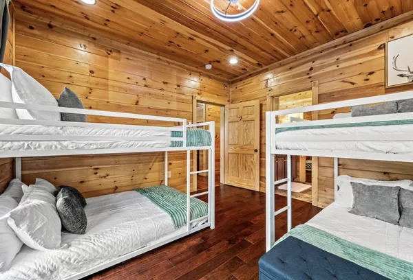 A bunk room with white metal bunks made up in white and grey linen.