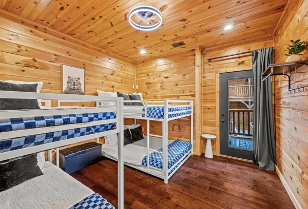 A second bunk room, bunks made up in blue and white under a pine ceiling.
