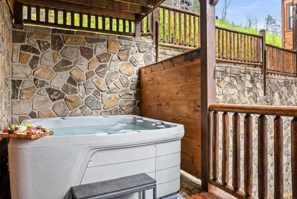 A hot tub set against a stone wall on an open deck.
