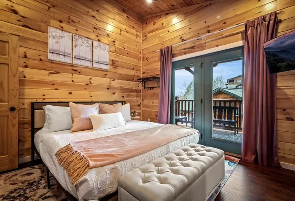 A king bed with a bench at its foot, facing tall doors onto the deck.