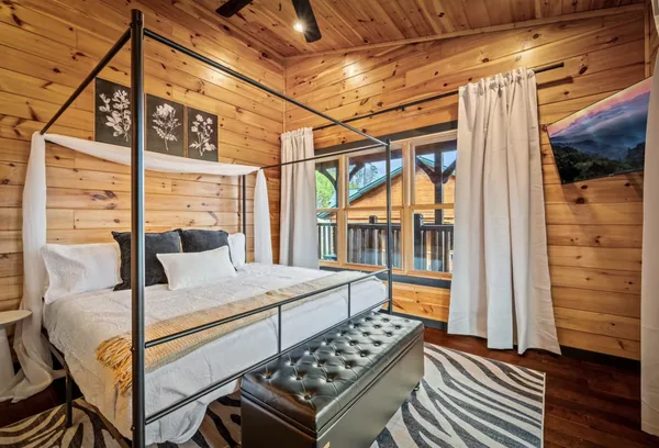 A four poster king bed with white linen, facing glass doors onto a private balcony.