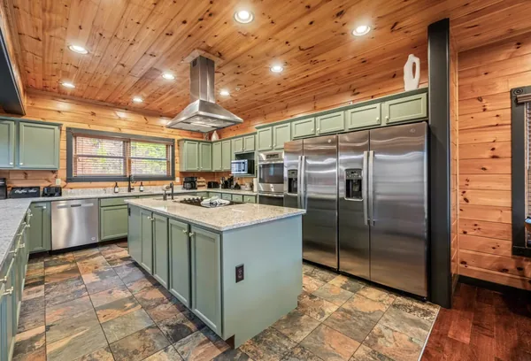 The kitchen, a green cabinet run with a stone island in the middle of it.