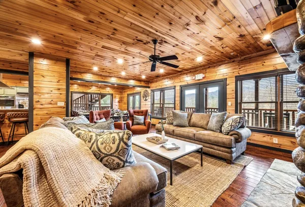 The living room from the far side, a throw over the arm of the sofa and the deck doors behind.
