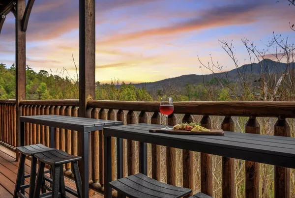 A high bar table along a deck rail, looking west to the ridge under a sunset sky.