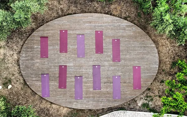 A circular wooden deck in the grounds at Armonia seen from above, mats laid out across it.