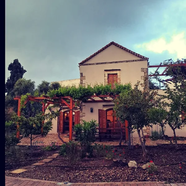 The stone house at Armonia at dusk, a vine pergola across its front.