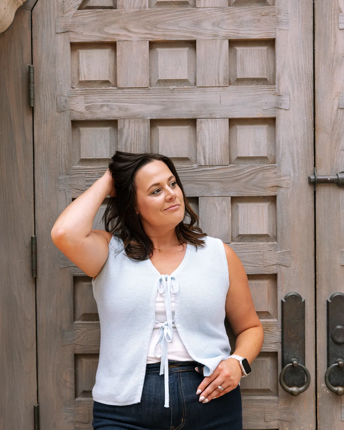 Cydnie Jocelyn laughing with a hand in her hair in front of an arched wooden door