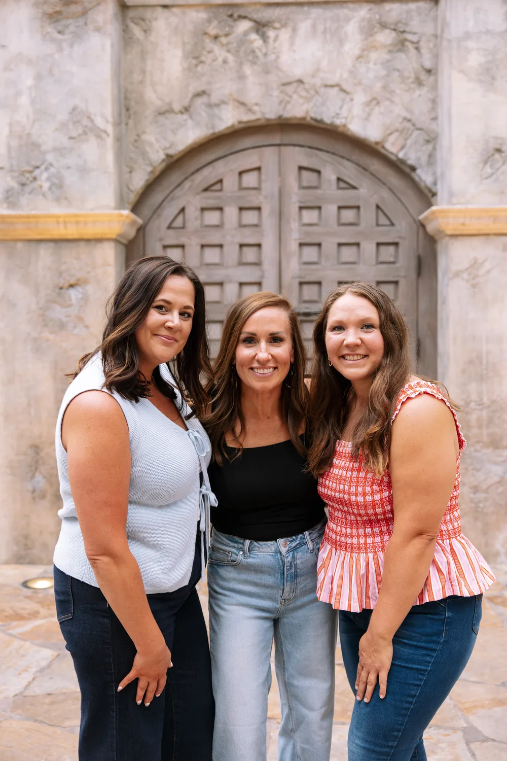 Cydnie and two women laughing together in front of a wooden door