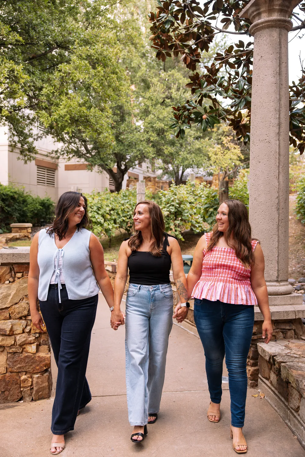 Cydnie walking arm in arm with two women along a garden path