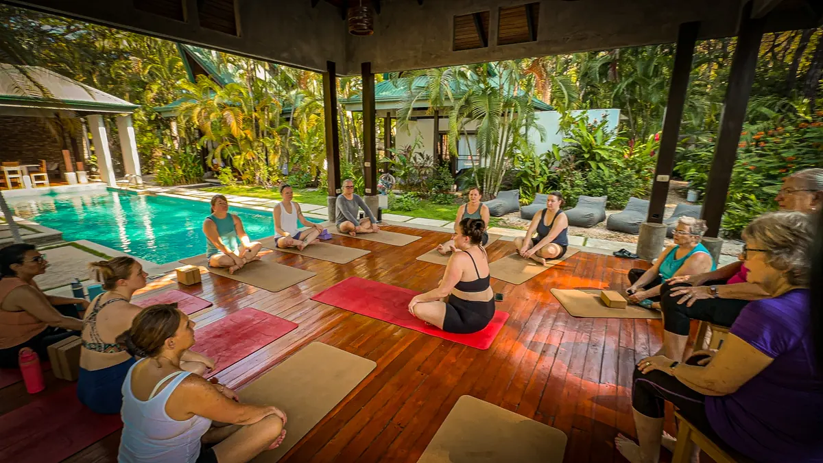 The open-sided pavilion at the Costa Rica retreat, mats and cushions laid out across the floor, the pool and the trees beyond it.